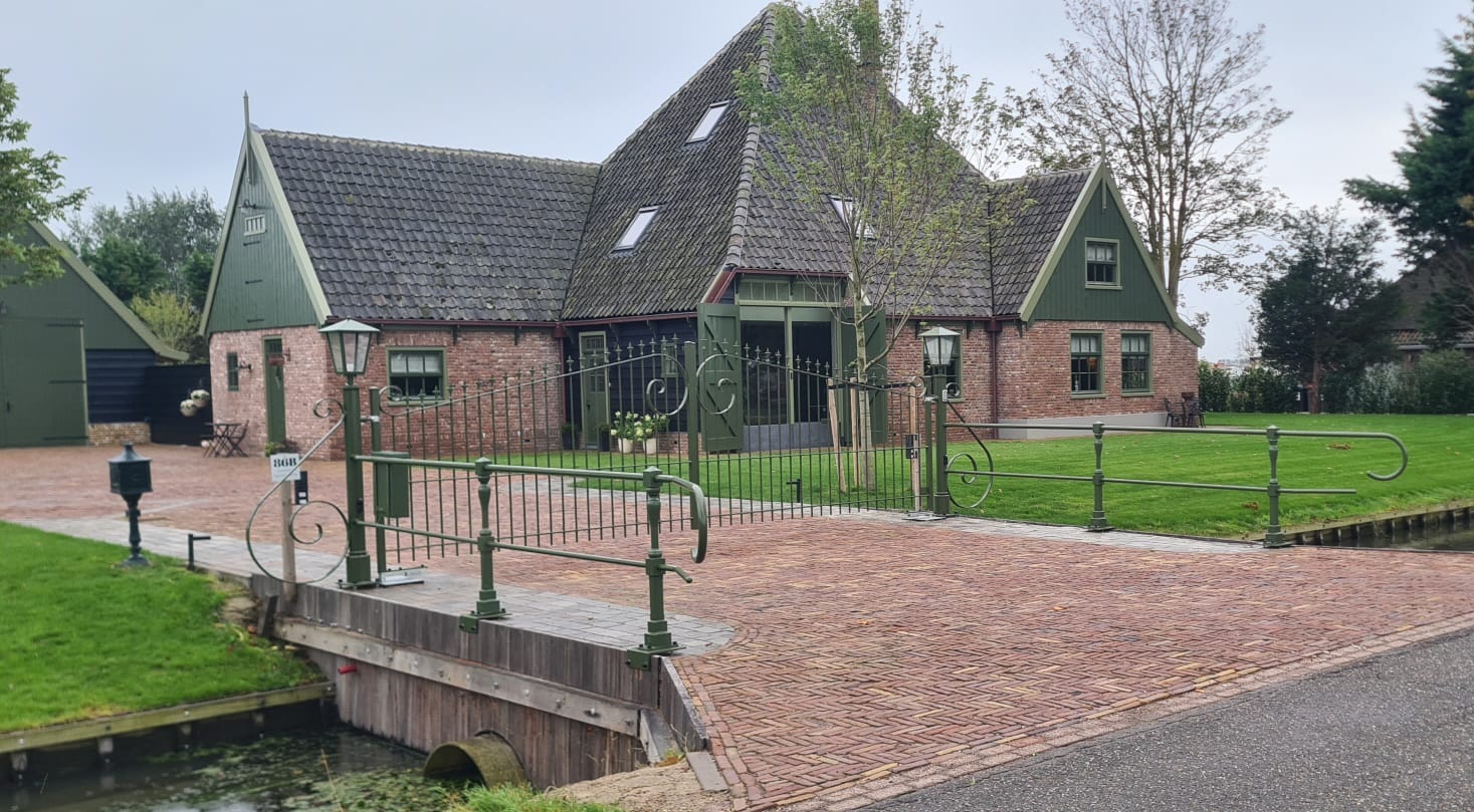 Ijzreen inrijpoort met krullen en sierspijlen met automatisering en bediening via intercom en telefoon app